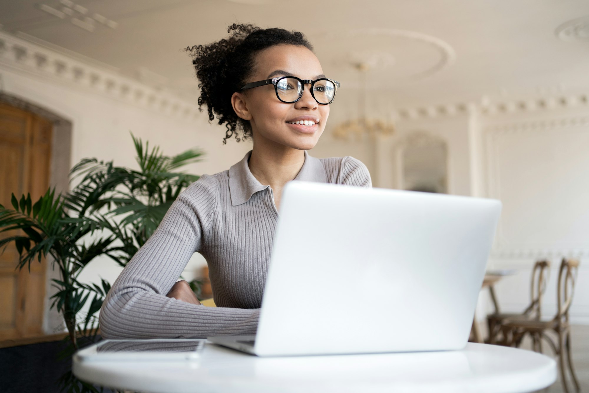 Cheerful professional woman with laptop, enjoying a productive day in a classic interior.