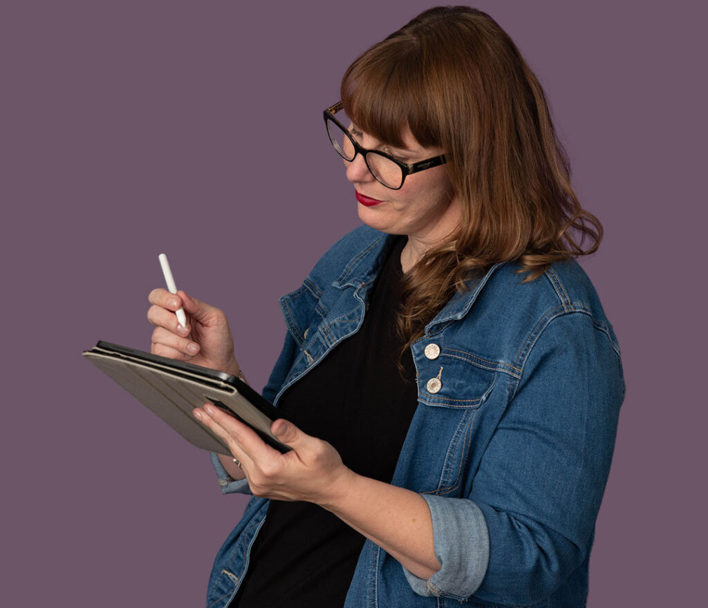 Woman in glasses writing on tablet with stylus