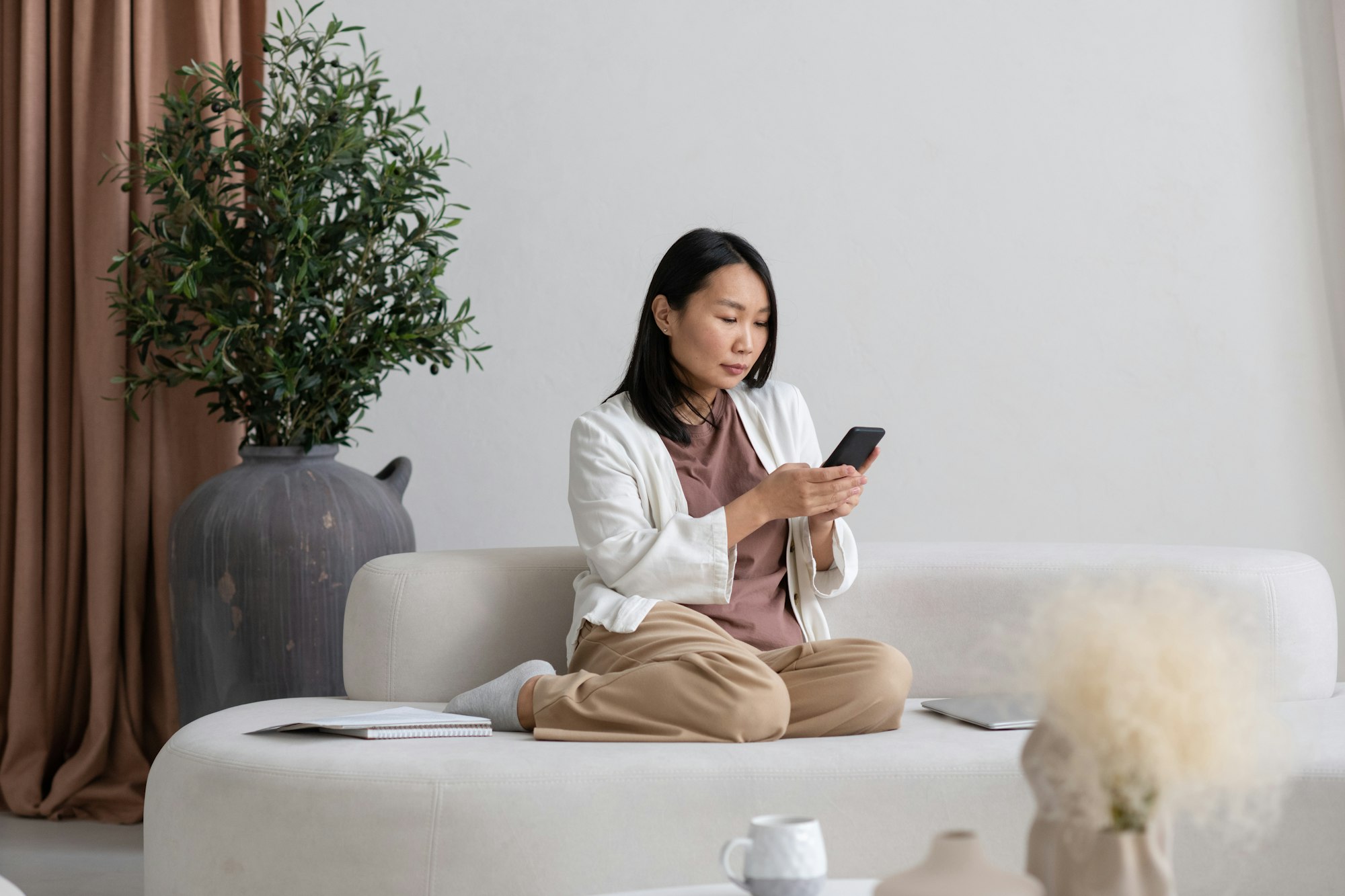 Young serious freelancer with smartphone texting or searching in the net