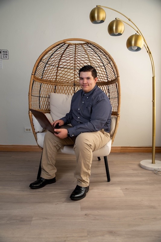 Young man sitting with laptop in modern chair