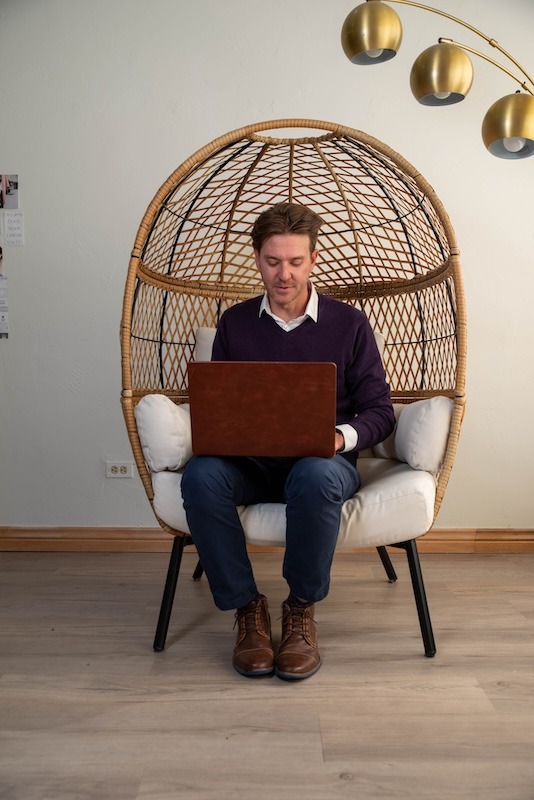 Man working on laptop in modern wicker chair