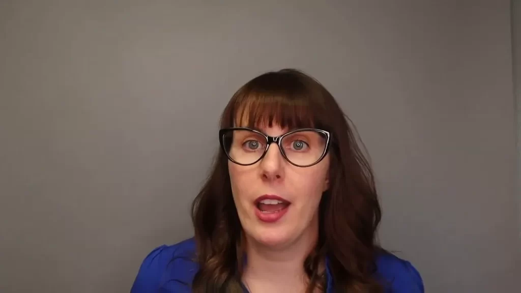 Woman in blue shirt wearing glasses speaking