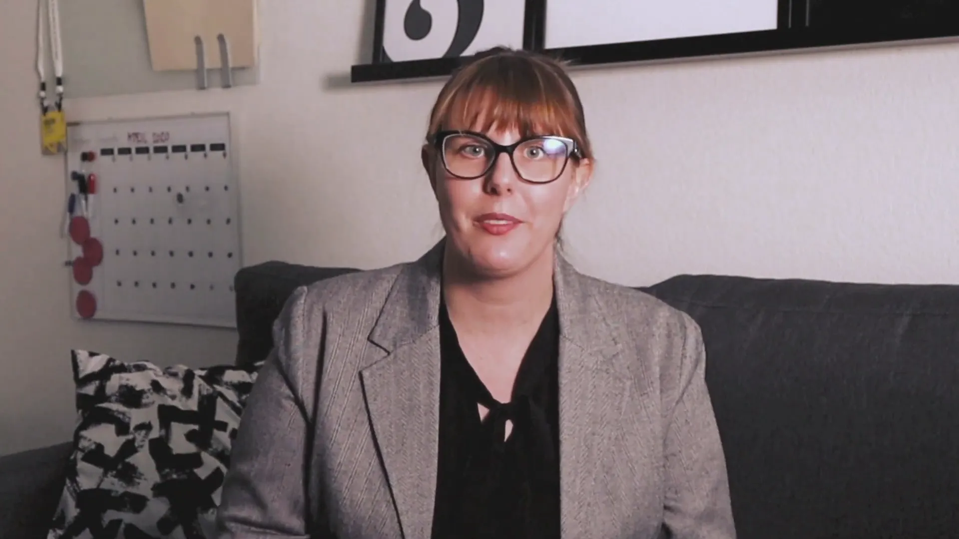 Woman in glasses sitting on couch during interview